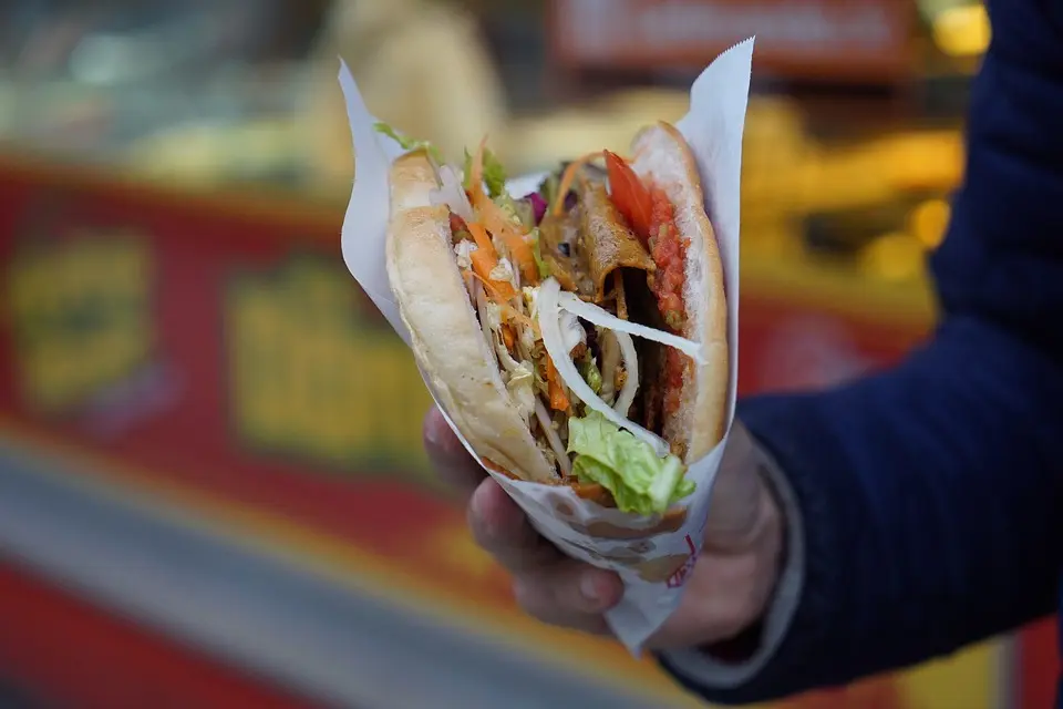 Kebab na wynos zapakowany w papierowe opakowanie trzymany w męskiej dłoni